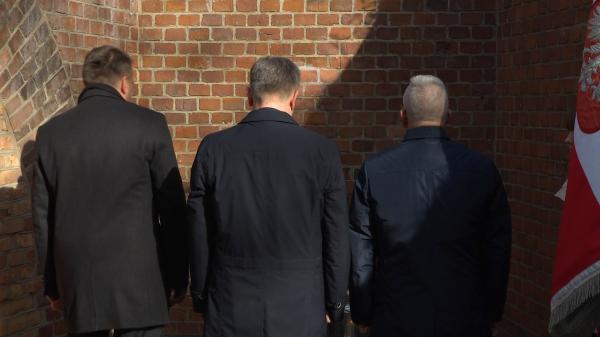 Marszałek Woźniak wraz z Mariuszem Wiśniewskim i Robertem Gawłem pochylają głowy przed ścianą śmierci - kliknij aby powiększyć