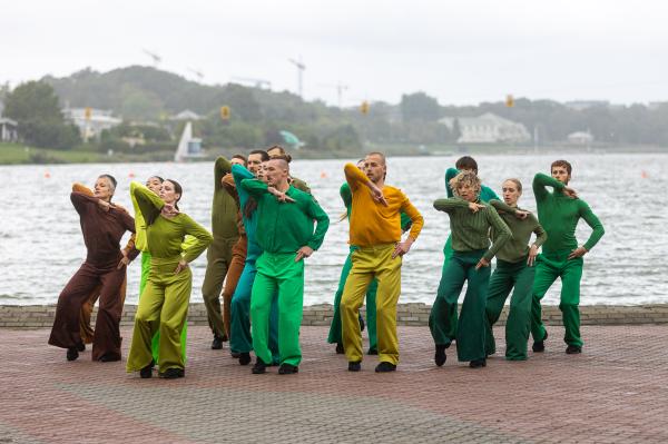 Na zdjęciu widać szesnastu tancerzy którzy wykonują różne ruchy. Tancerze są ubrani w stroje żółte i zielone - kliknij aby powiększyć