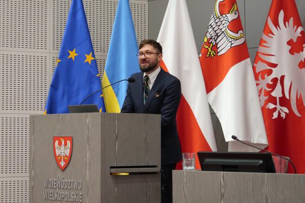 Pan Miłosz Jakubowski -radca prawny specjalizujący się w prawie ochrony środowiska wygłaszający przy mównicy prezentację o prawnych aspektach kontroli przestrzegania zapisów uchwał antysmogowych - kliknij aby powiększyć